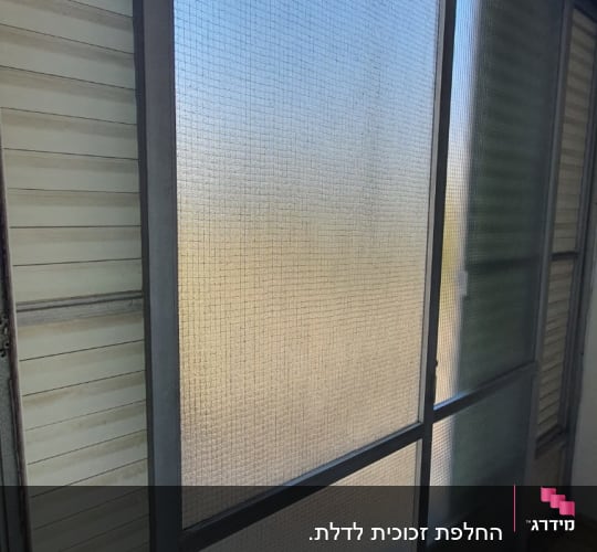 חלון זכוכית עם מסגרת מתכת ורשת פנימית